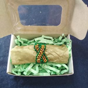 A handcrafted ring featuring gold and green Czech glass beads. Measuring approximately 7cm in circumference.