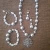 20240115_102504 White Flower Pendant Necklace Set - Elegant jewelry ensemble with metal pendant and white beads.