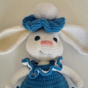 Crocheted white bunny toy wearing a blue dress, shoes and hat, approximately 40cm tall, crafted in South Africa.