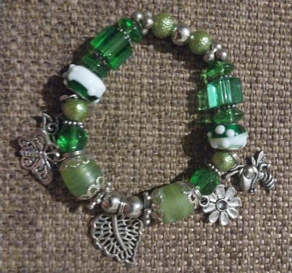 Green Leaf Necklace Set - A collection of green glass beads, silver spacers, a large silver leaf pendant, matching bracelet, and earrings.