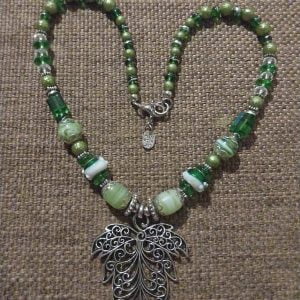 Green Leaf Necklace Set - A collection of green glass beads, silver spacers, a large silver leaf pendant, matching bracelet, and earrings.