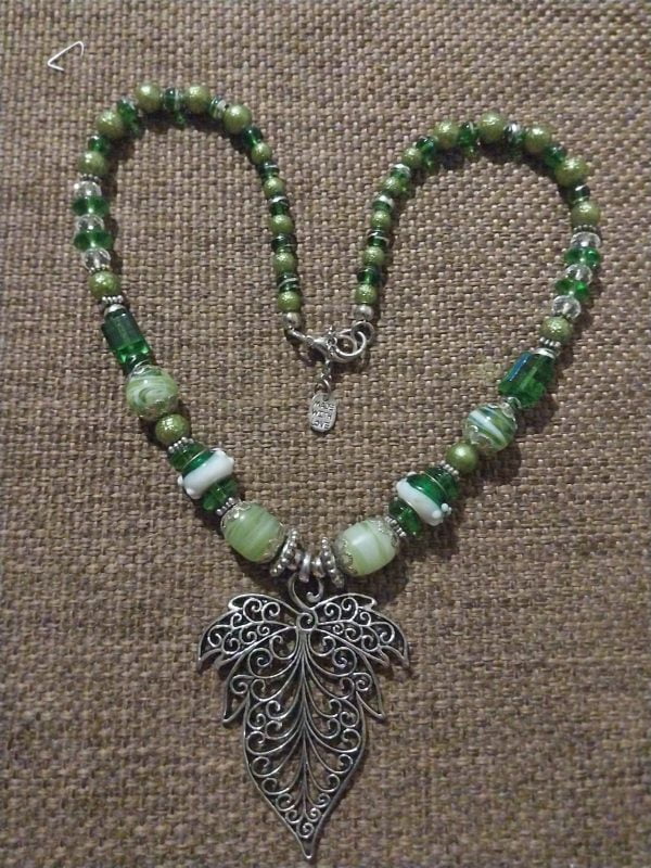 Green Leaf Necklace Set - A collection of green glass beads, silver spacers, a large silver leaf pendant, matching bracelet, and earrings.