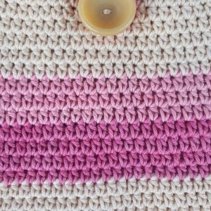 A pink and white crocheted cotton casual shoulder bag with a button closure.